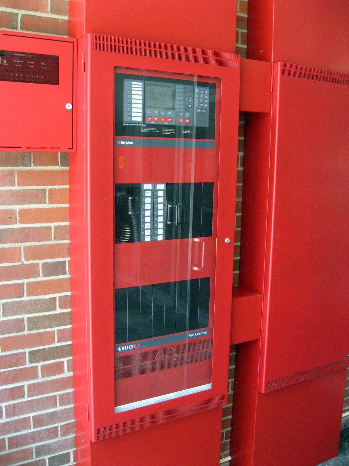 Simplex 4100U fire alarm control panel on a brick wall