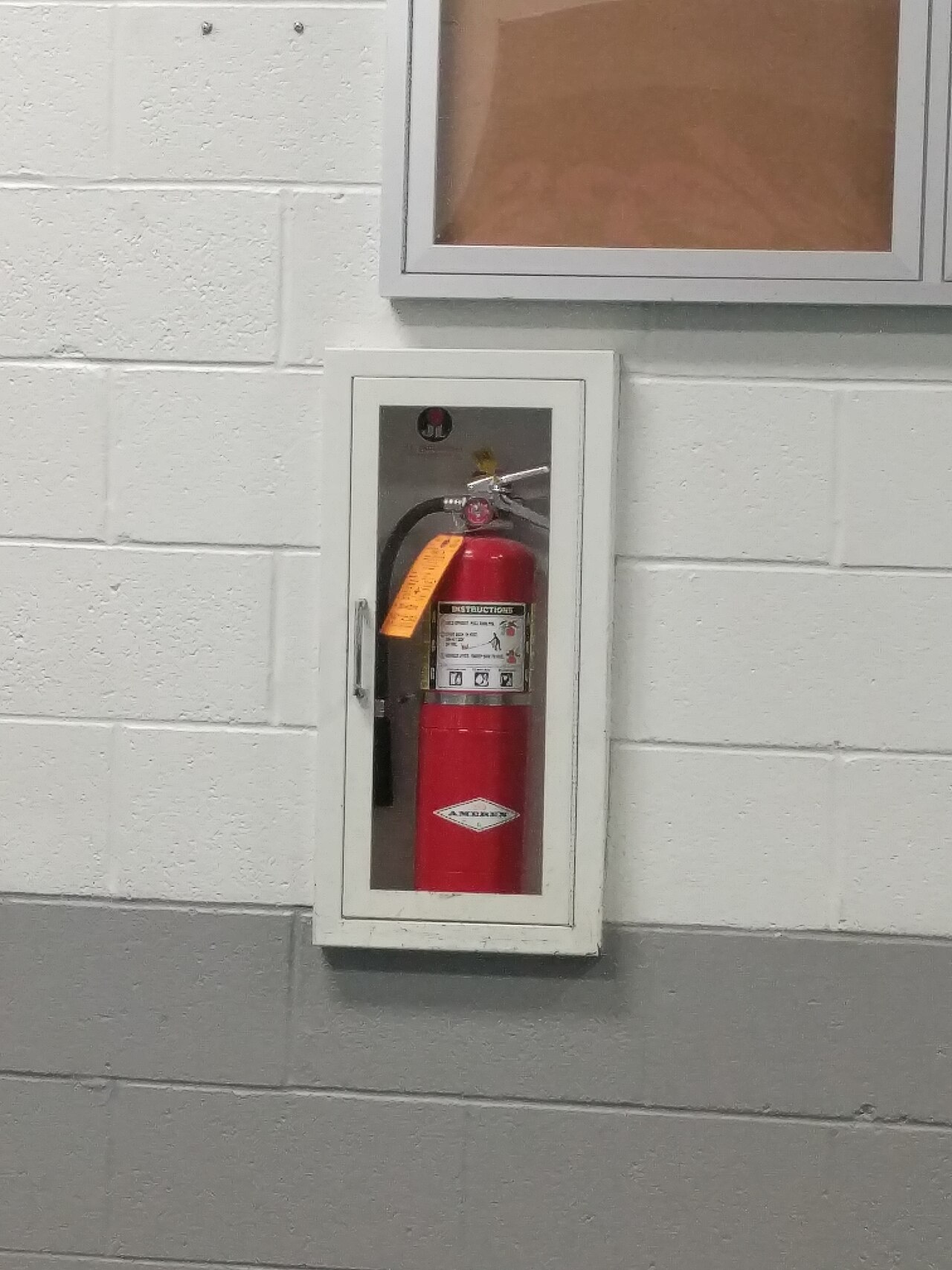 Amerex portable fire extinguisher in a J.L. Industries wall cabinet with an inspection tag
